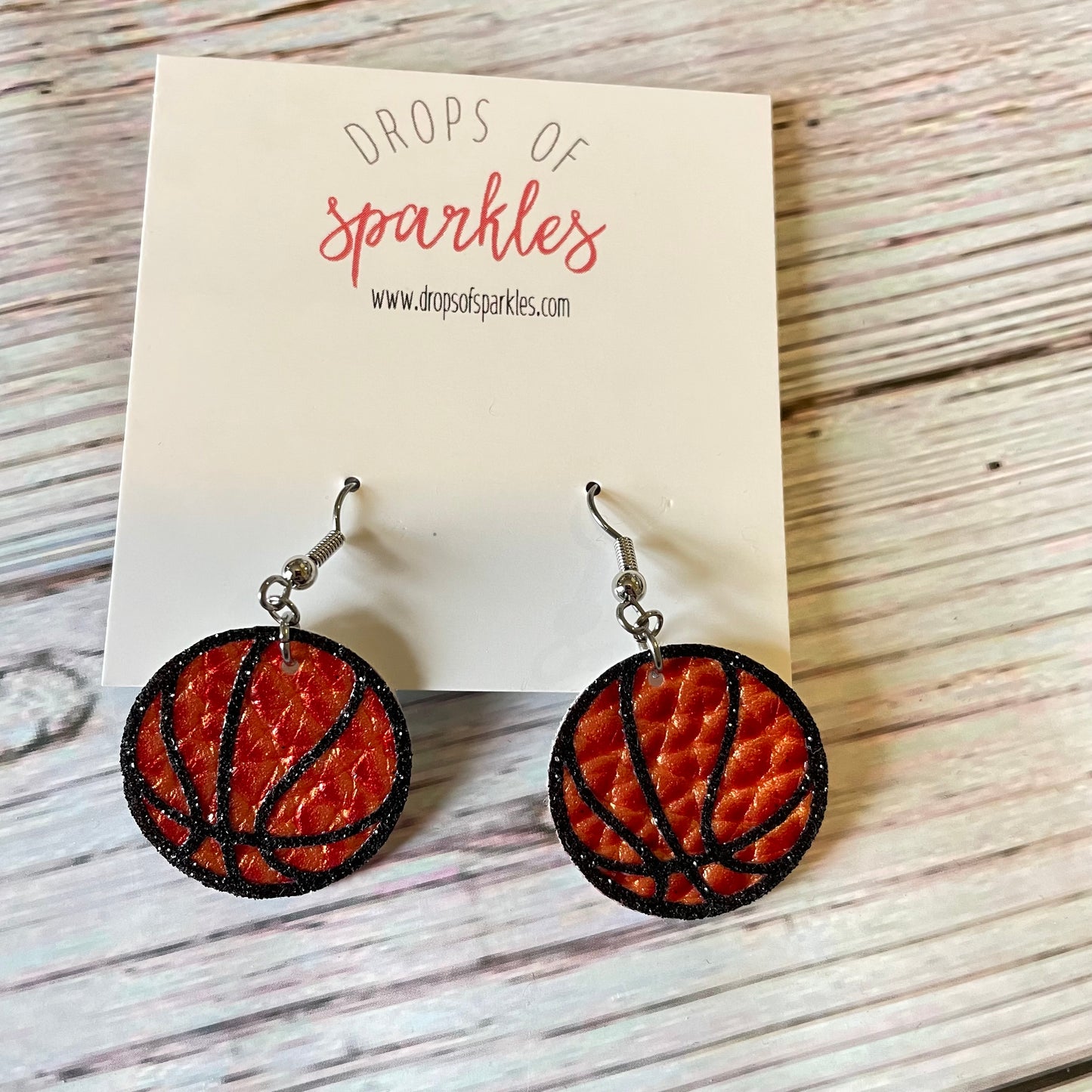 Basketball earrings made of faux orange pebbled leather with black glitter vinyl shown in 1 inch size.