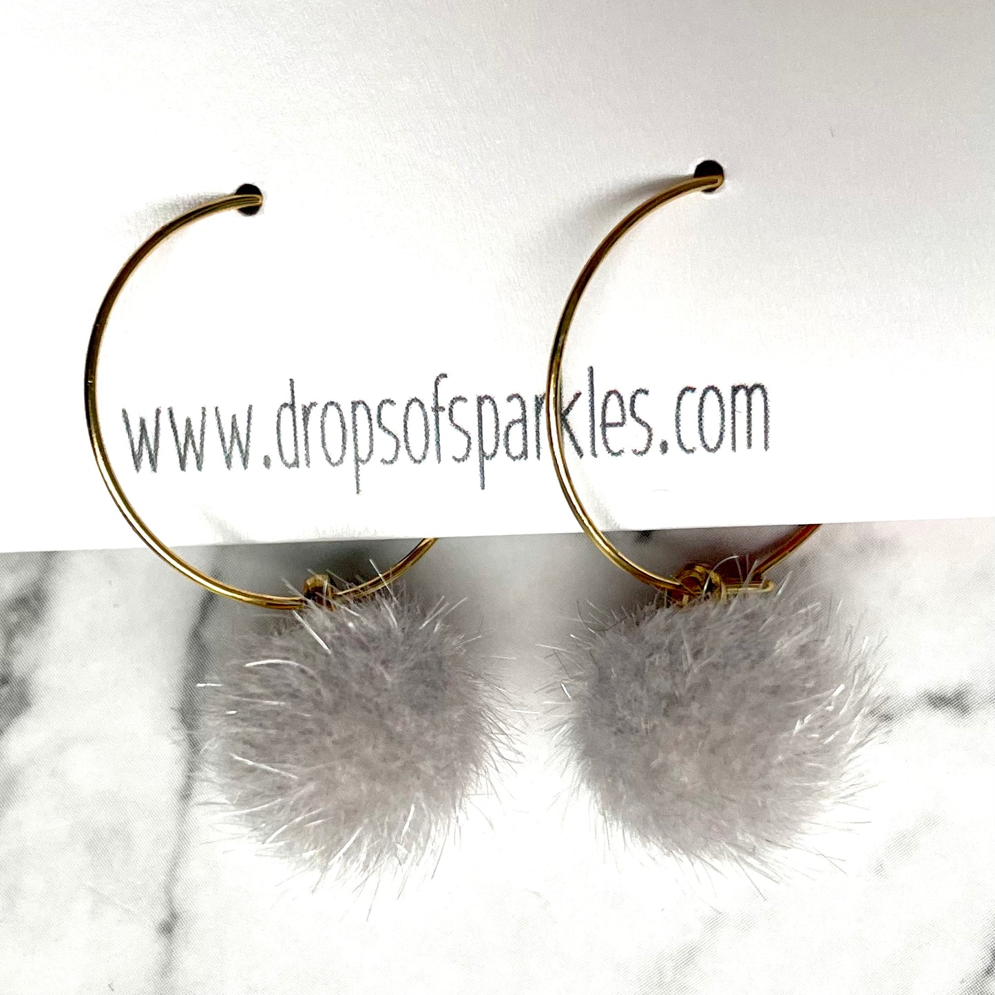 20mm round 24k shiny gold plated  "hoops" with fun little smokey gray fuzzy pom poms attached