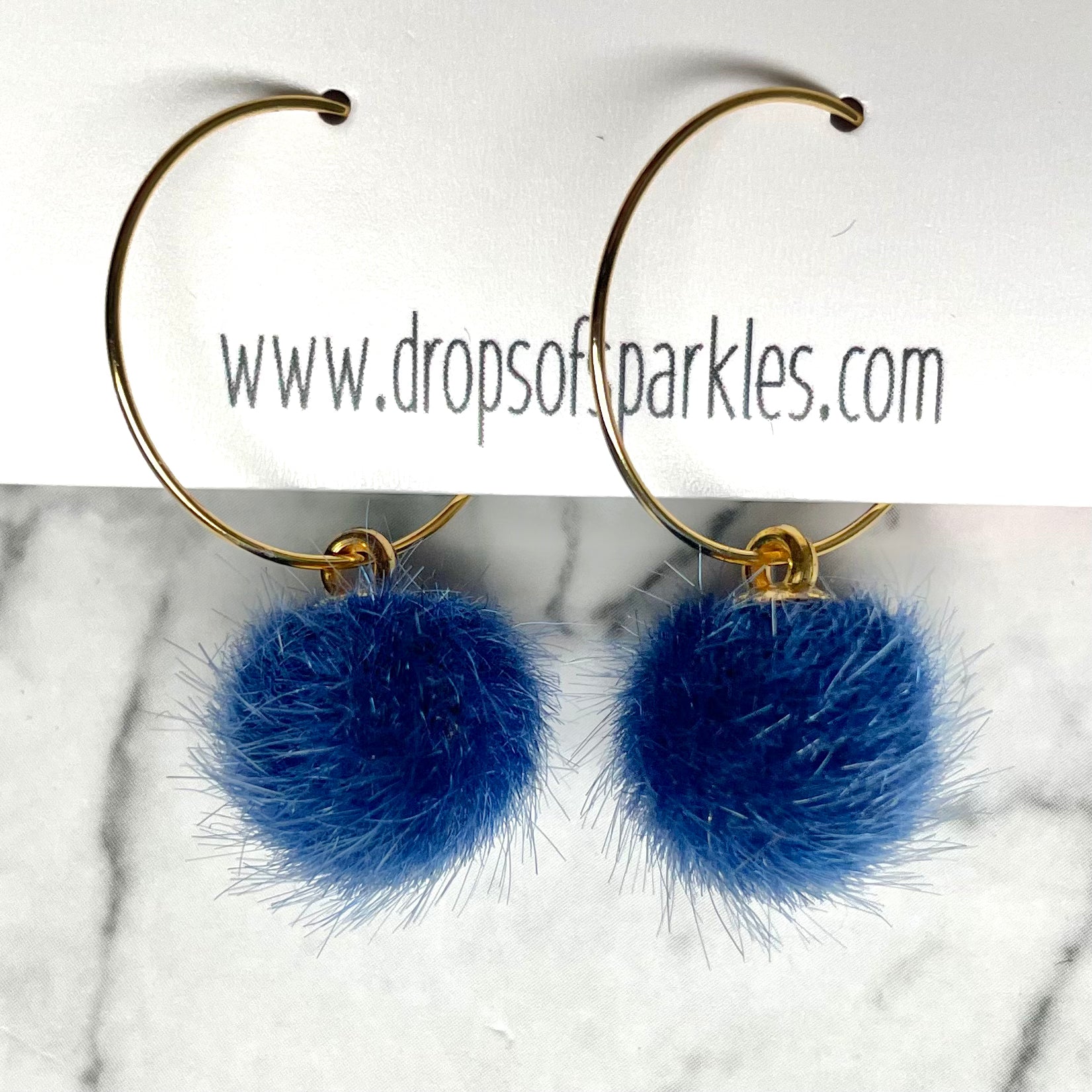 20mm round 24k shiny gold plated  "hoops" with fun little navy blue fuzzy pom poms attached