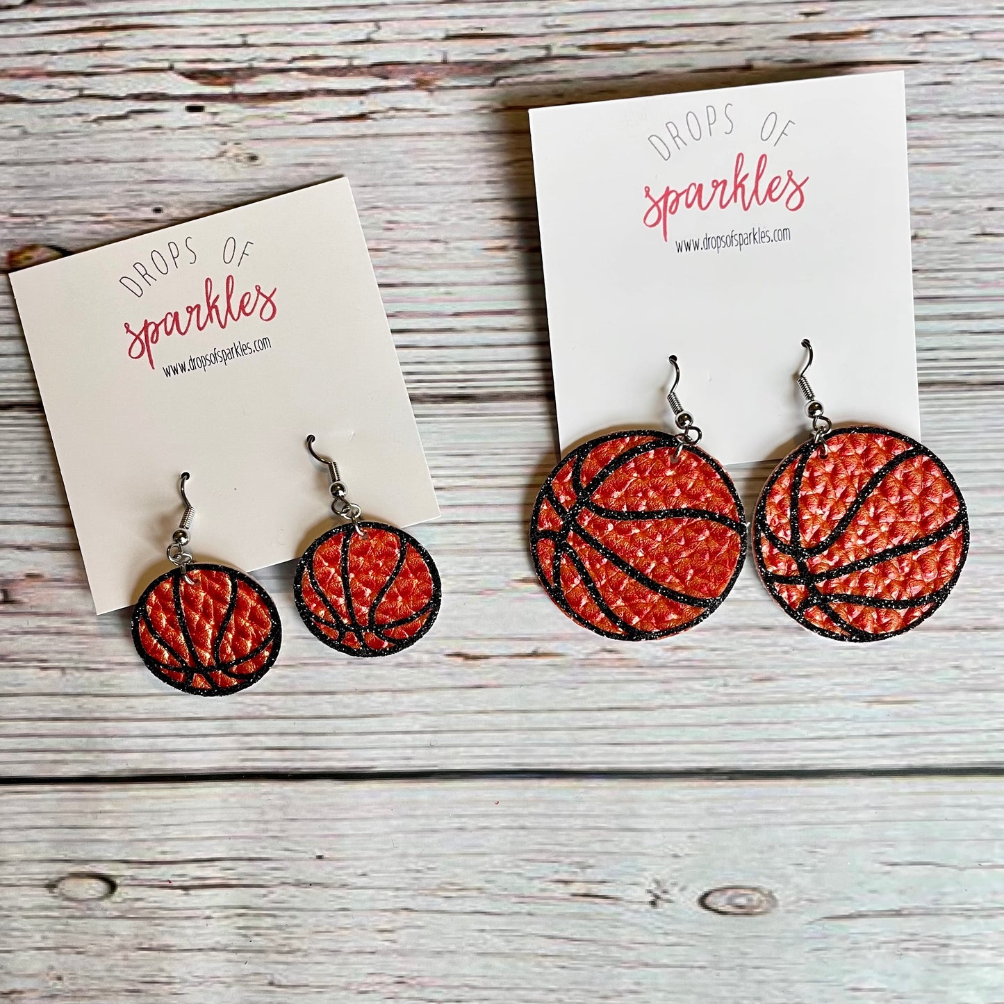 Basketball earrings made of faux orange pebbled leather with black glitter vinyl shown in either 1 inch or 2 inch sizes.